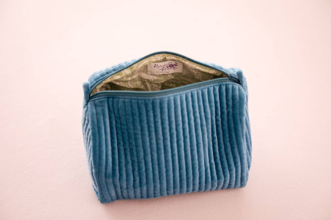 Blue quilted pouch with a visible brand logo on a light pink background