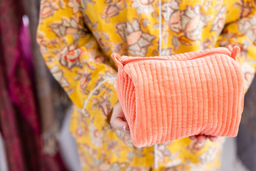 Person holding a pink textured pouch with a blurred background
