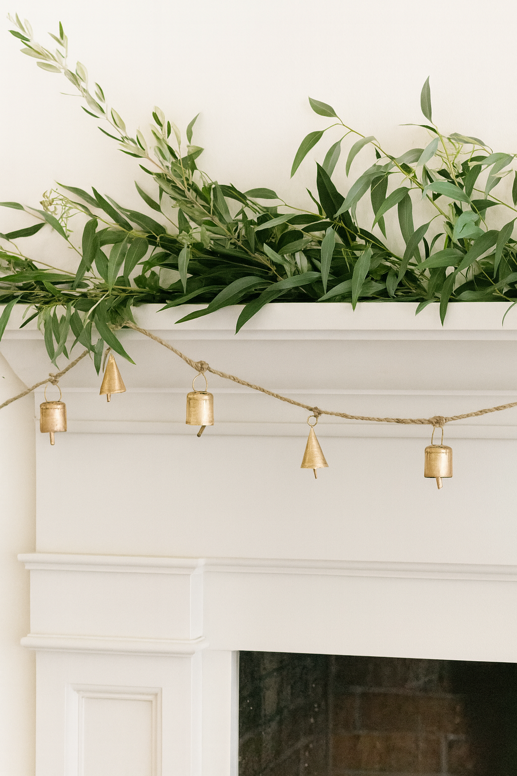 Decorative greenery on a mantelpiece with gold bell garland