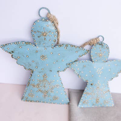 Decorative angel-shaped ornaments with gold snowflake patterns on a light blue background.